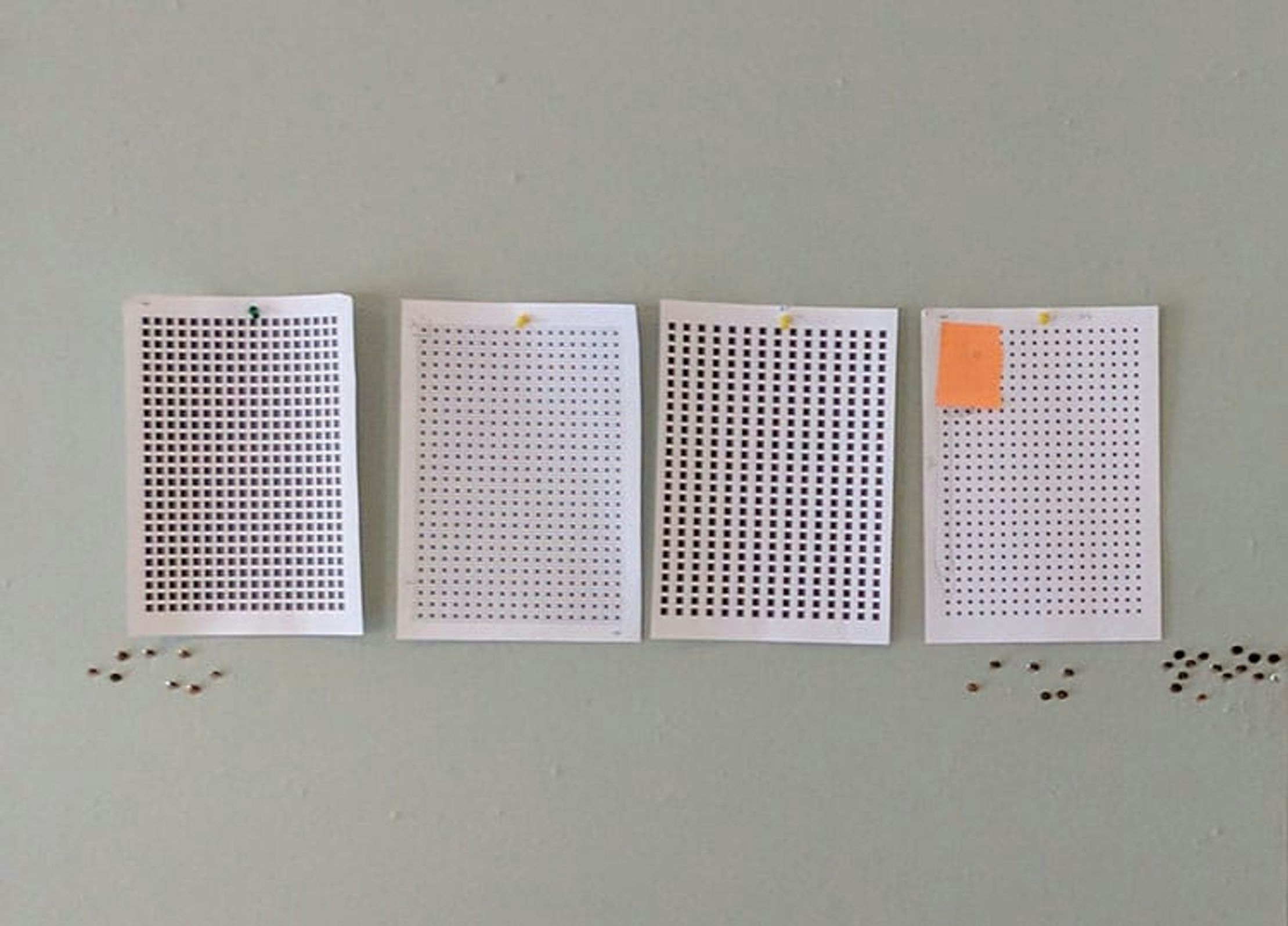 Four sheets of paper pinned to a board and printed with grids of different dot sizes, used to test their visibility at a distance.